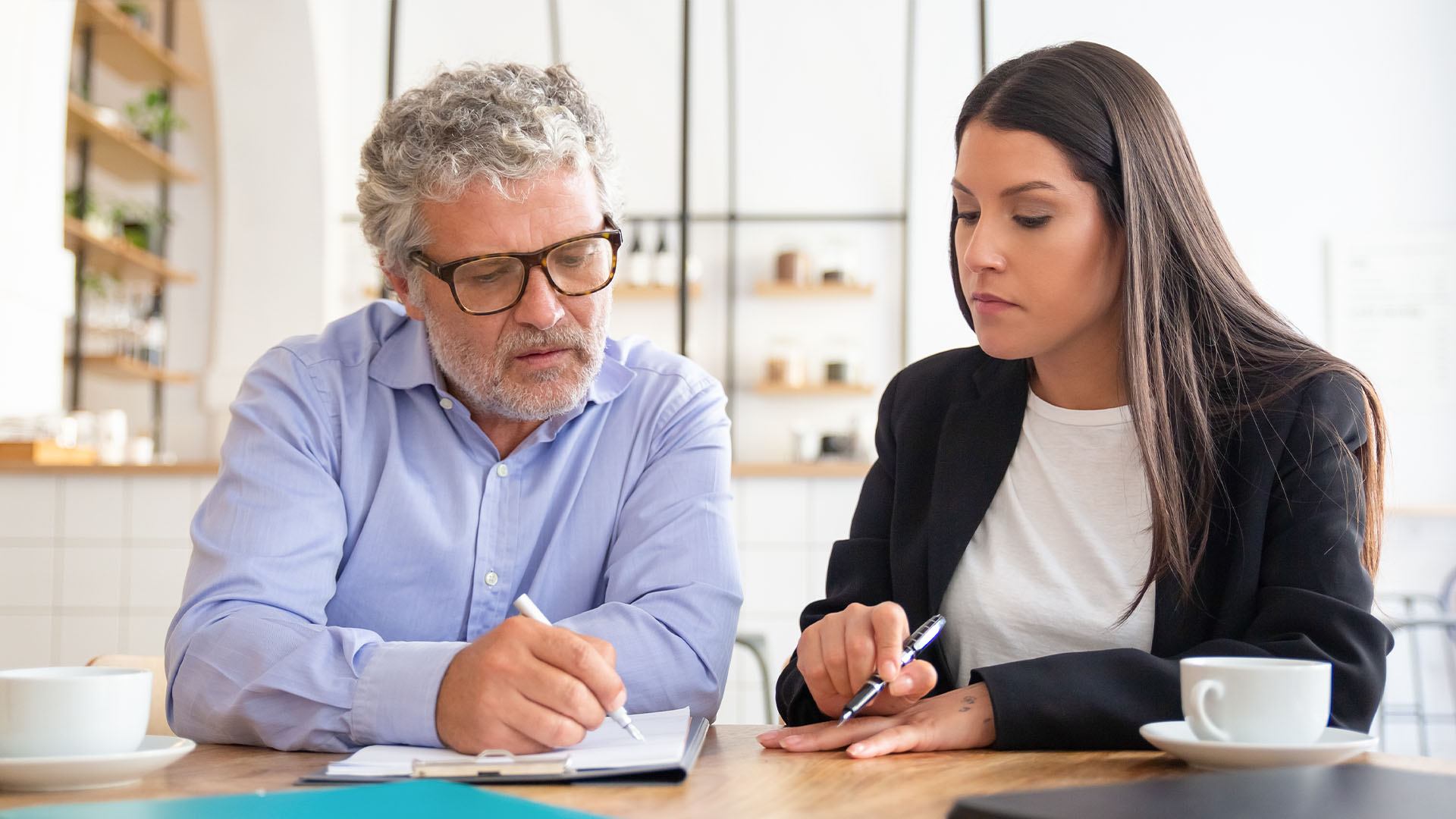 A man and a woman sitting next to each other discussing over a document