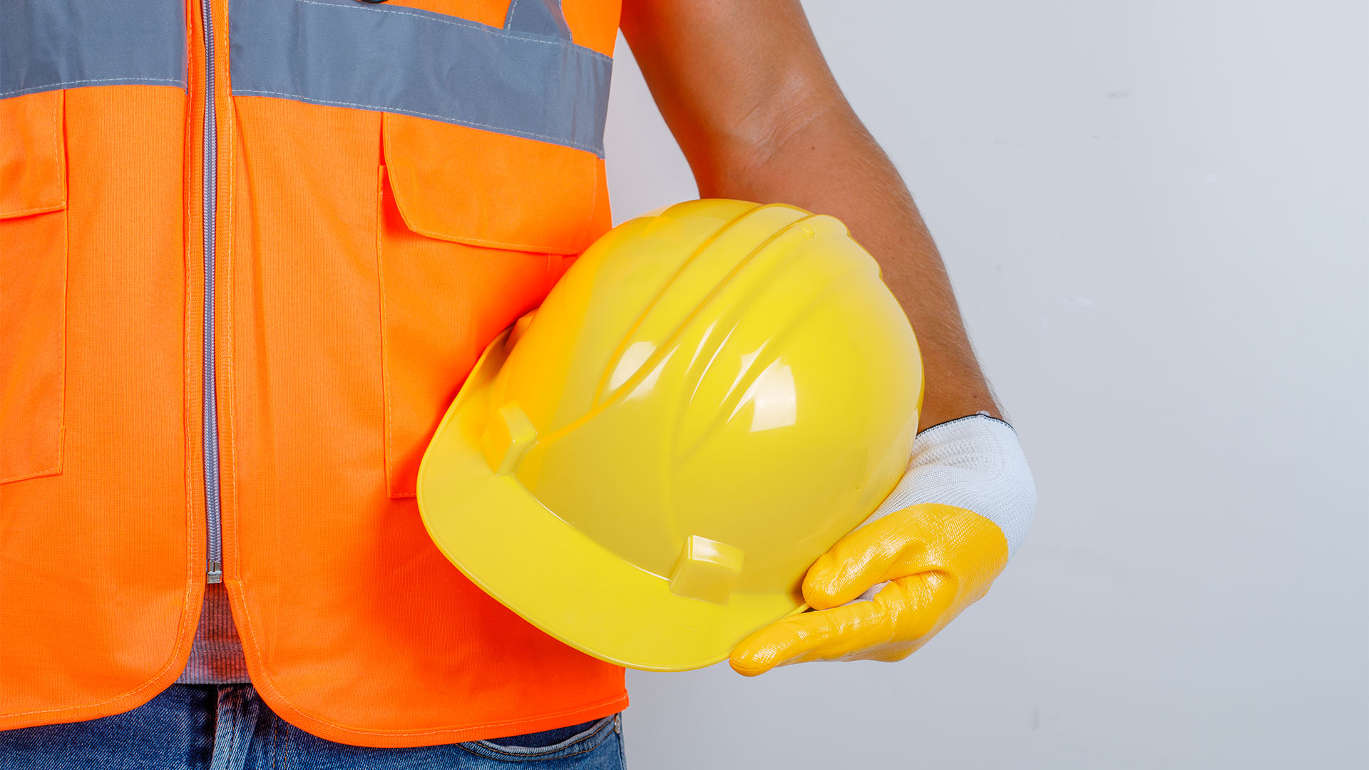 A man in a construction vest holding a yellow hard hat